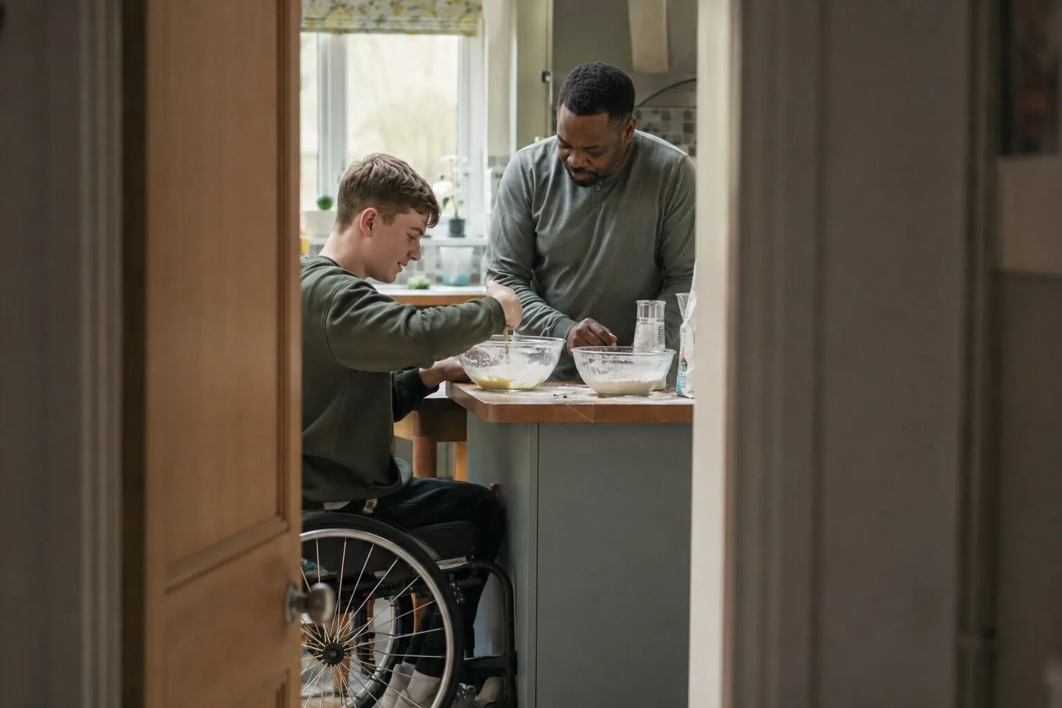 A child using a wheelchair and an adult doing an activity at the table
