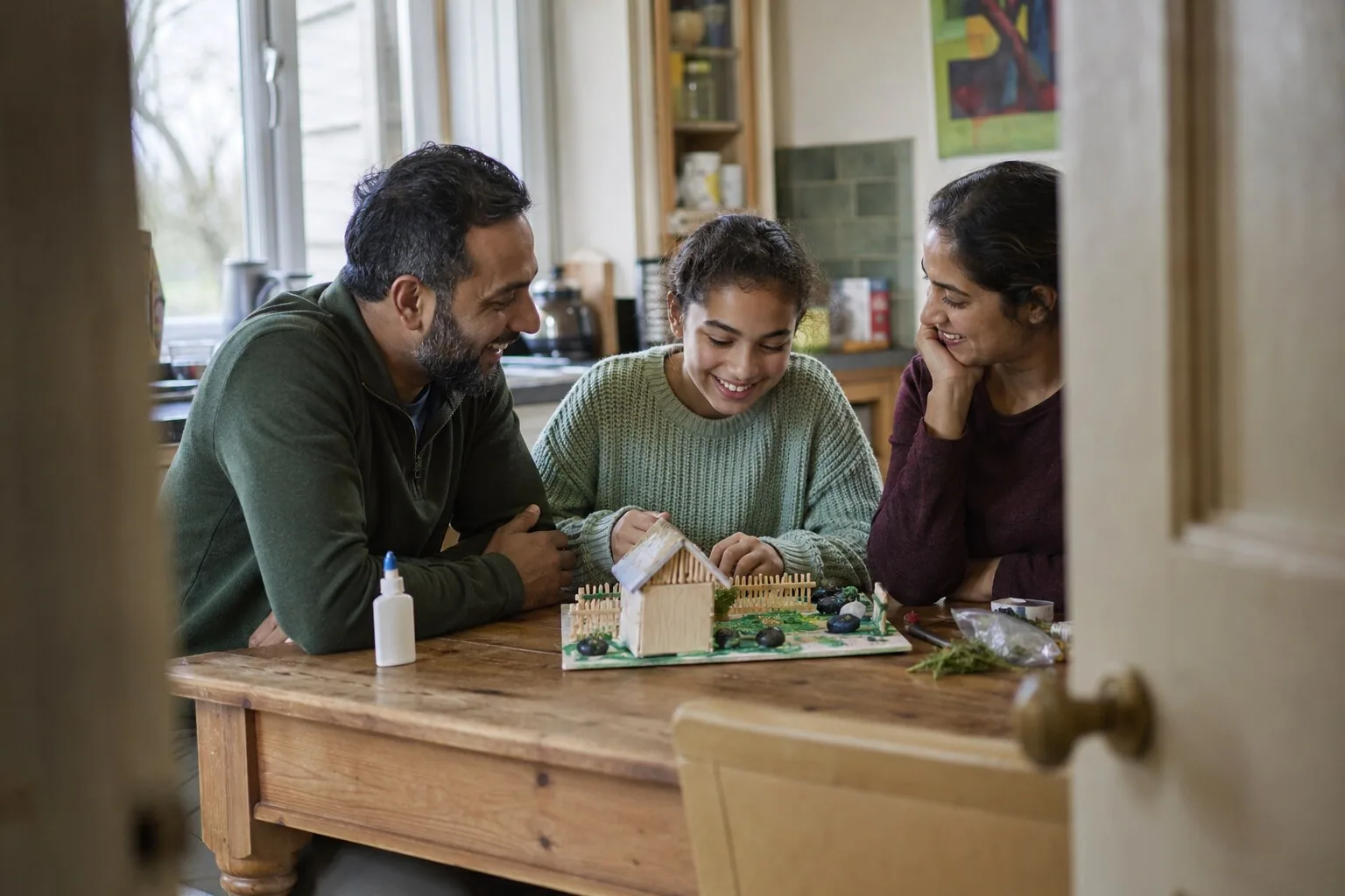 An adult and two teenagers looking at a model house they have made