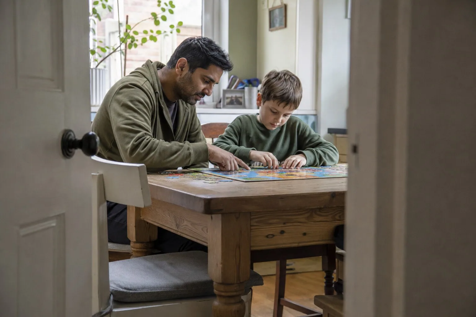 A man and a child working on a puzzle at the table