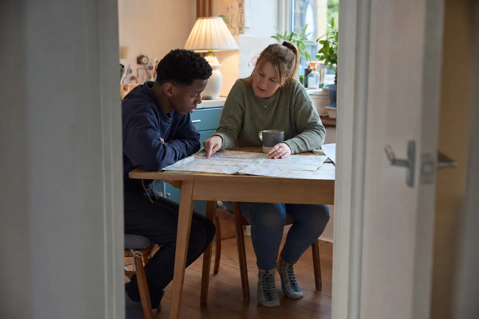 An adult and a young person looking at a map together at home