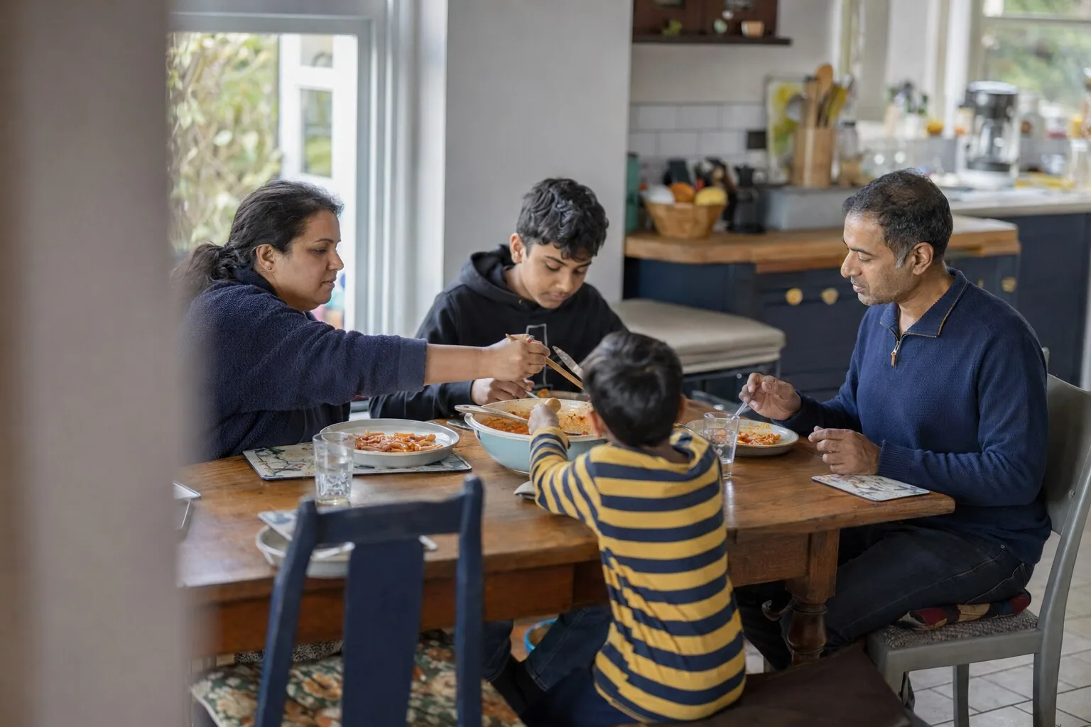Adults and children sharing a meal around the kitchen table