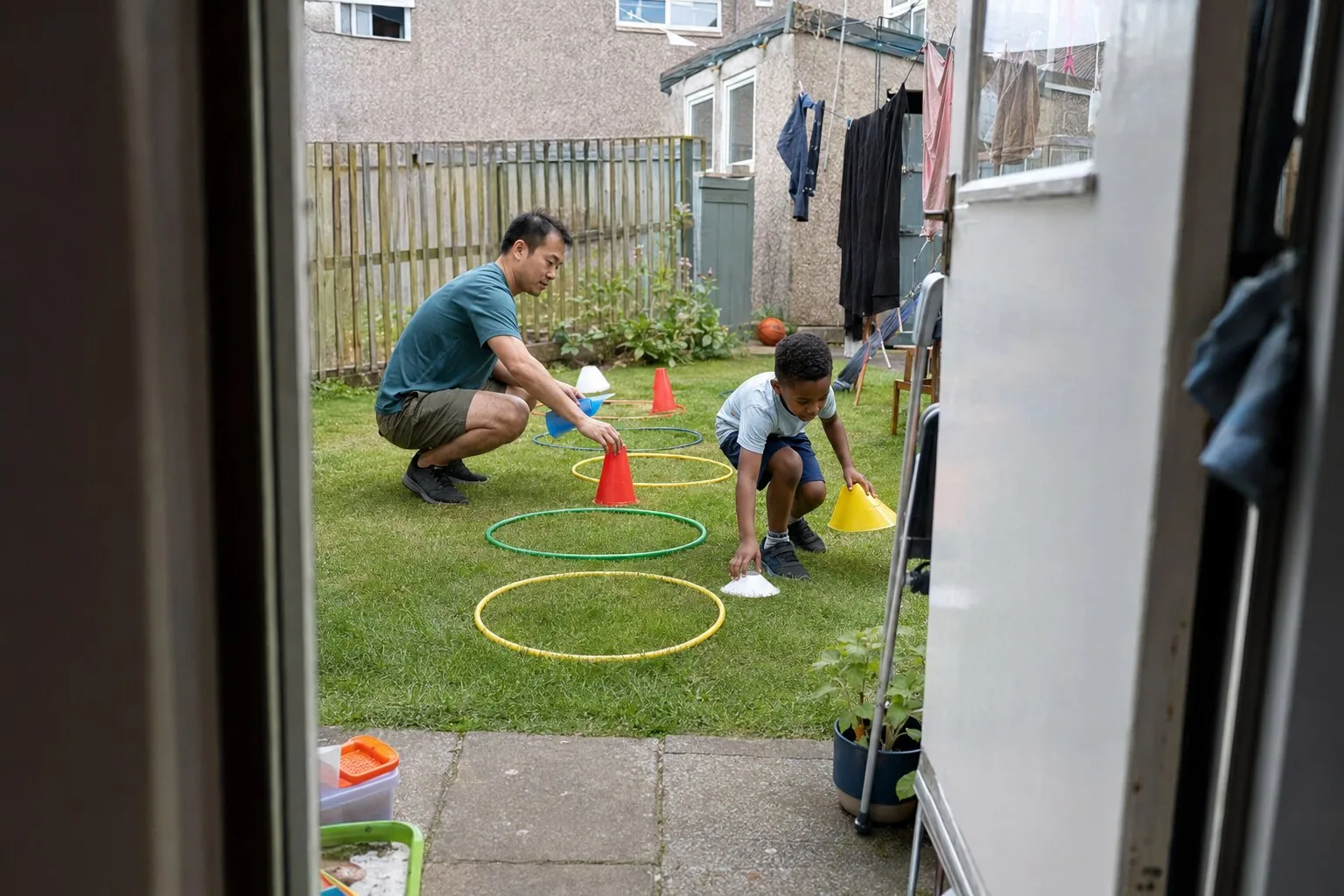 An adult and a child playing with hoops and cones in the garden