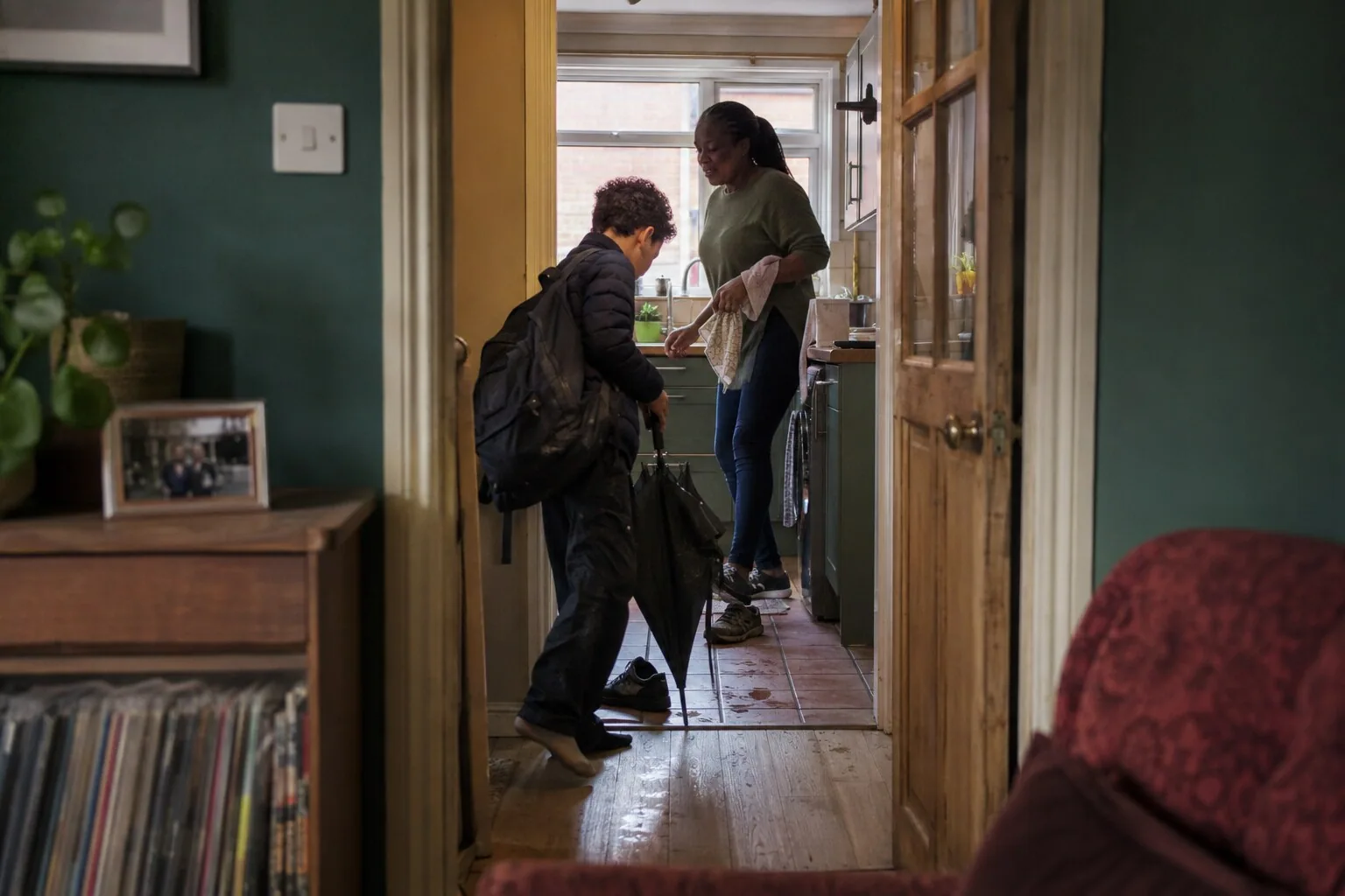 An adult greeting a young person coming through the front door