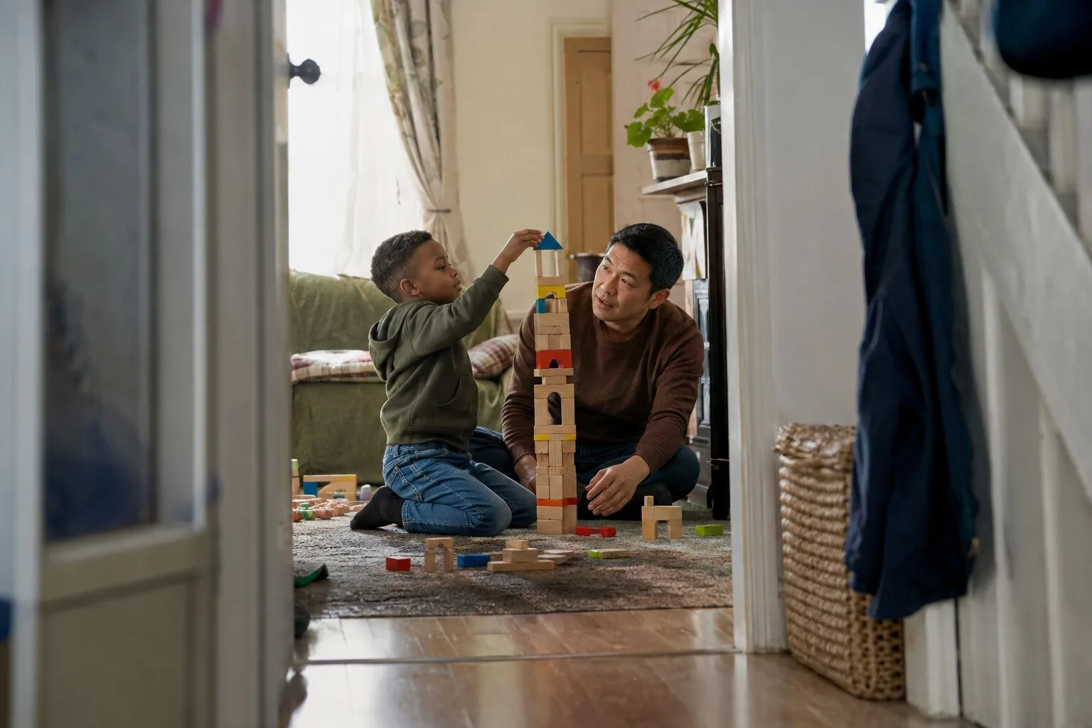 An adult and a child building a tall tower with toy blocks