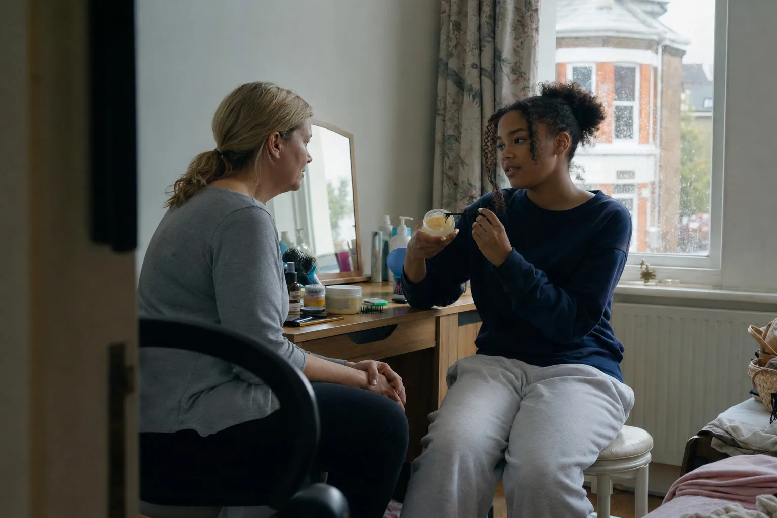 A teenager sharing a small object with an adult beside the window