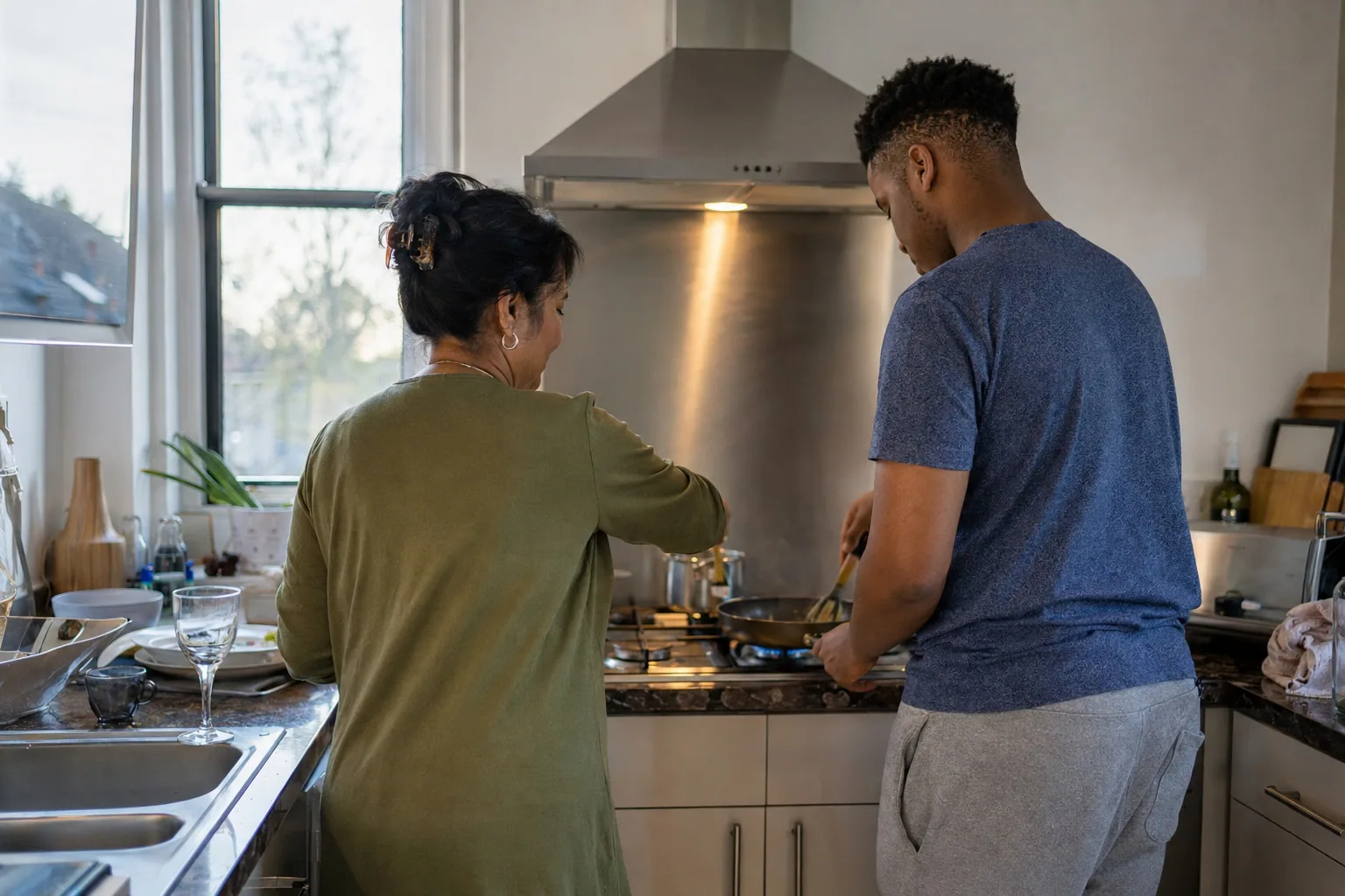An adult and a young person cooking together at the hob