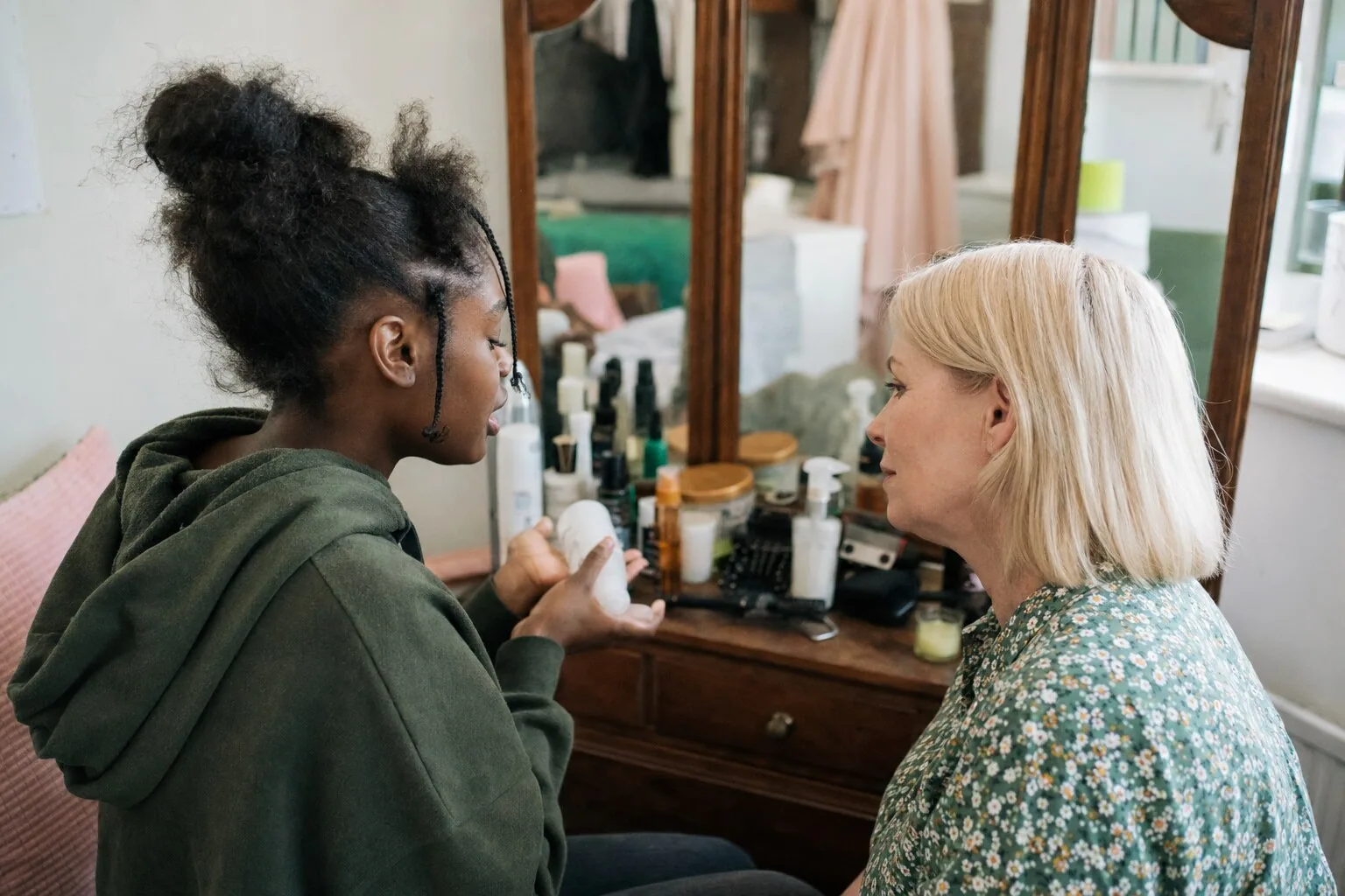 Two people talking together beside a mirror at home
