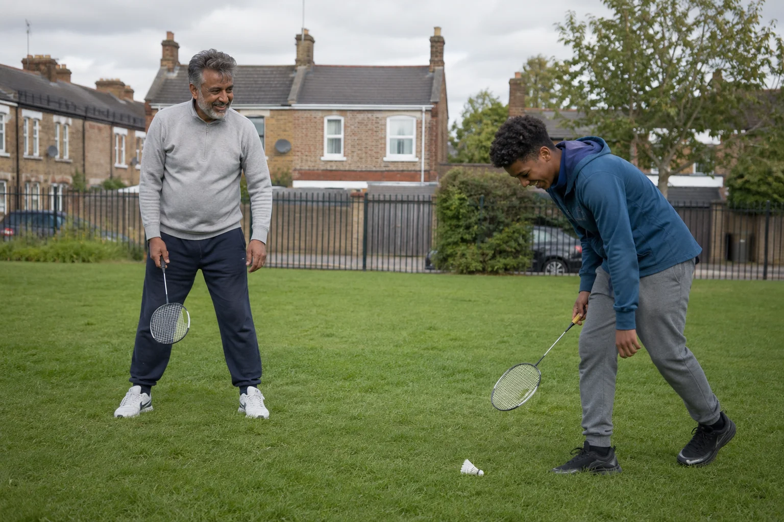 A man and a teenager enjoying a casual game of badminton