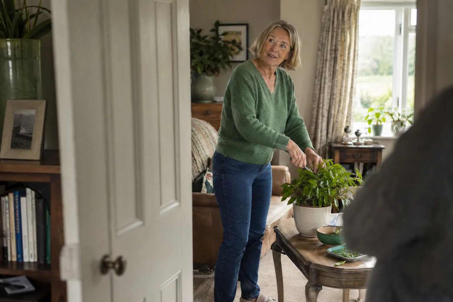 A woman tending a plant while chatting at home