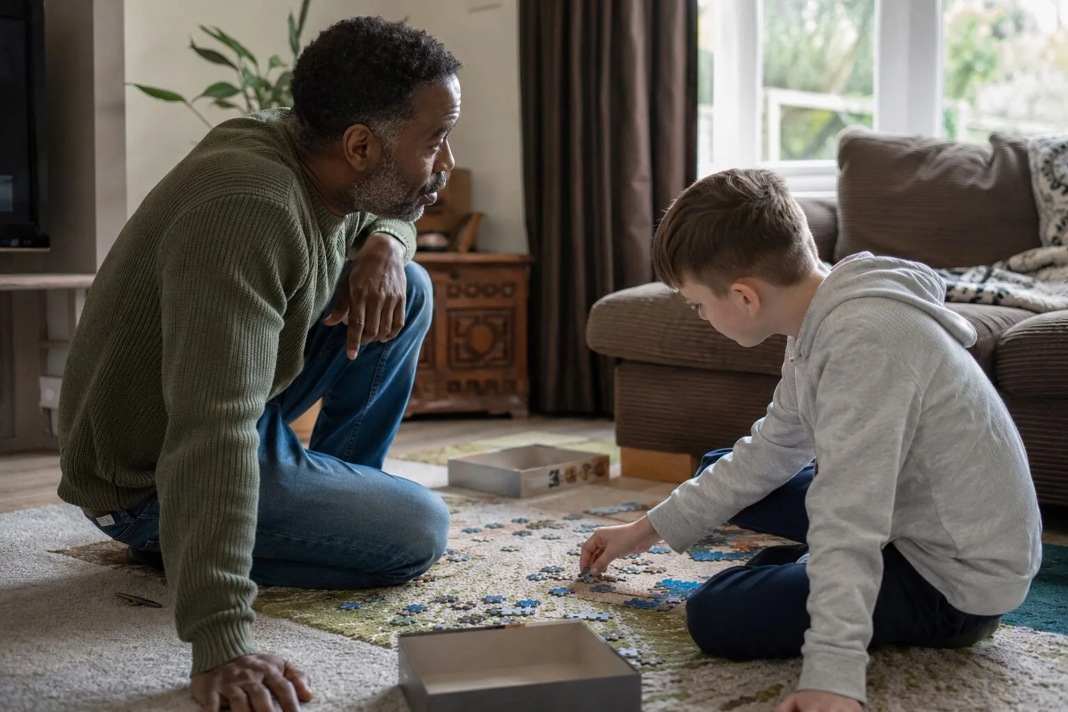 An adult and a child working on a jigsaw on the living-room floor