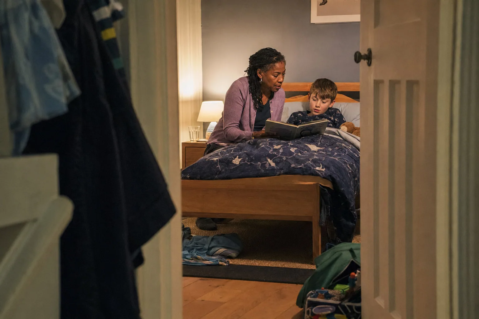 An adult reading a book with a child at bedtime