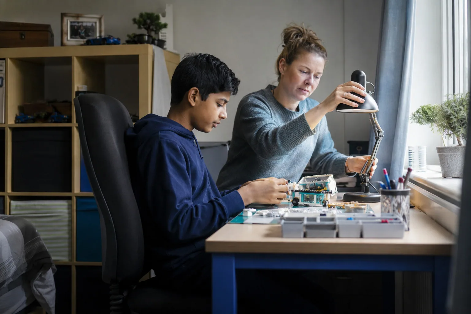 An adult and a teenager working on a small electronics project