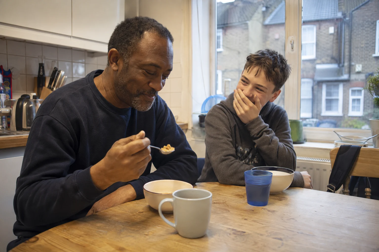 A man and a teenager sharing a joke over breakfast
