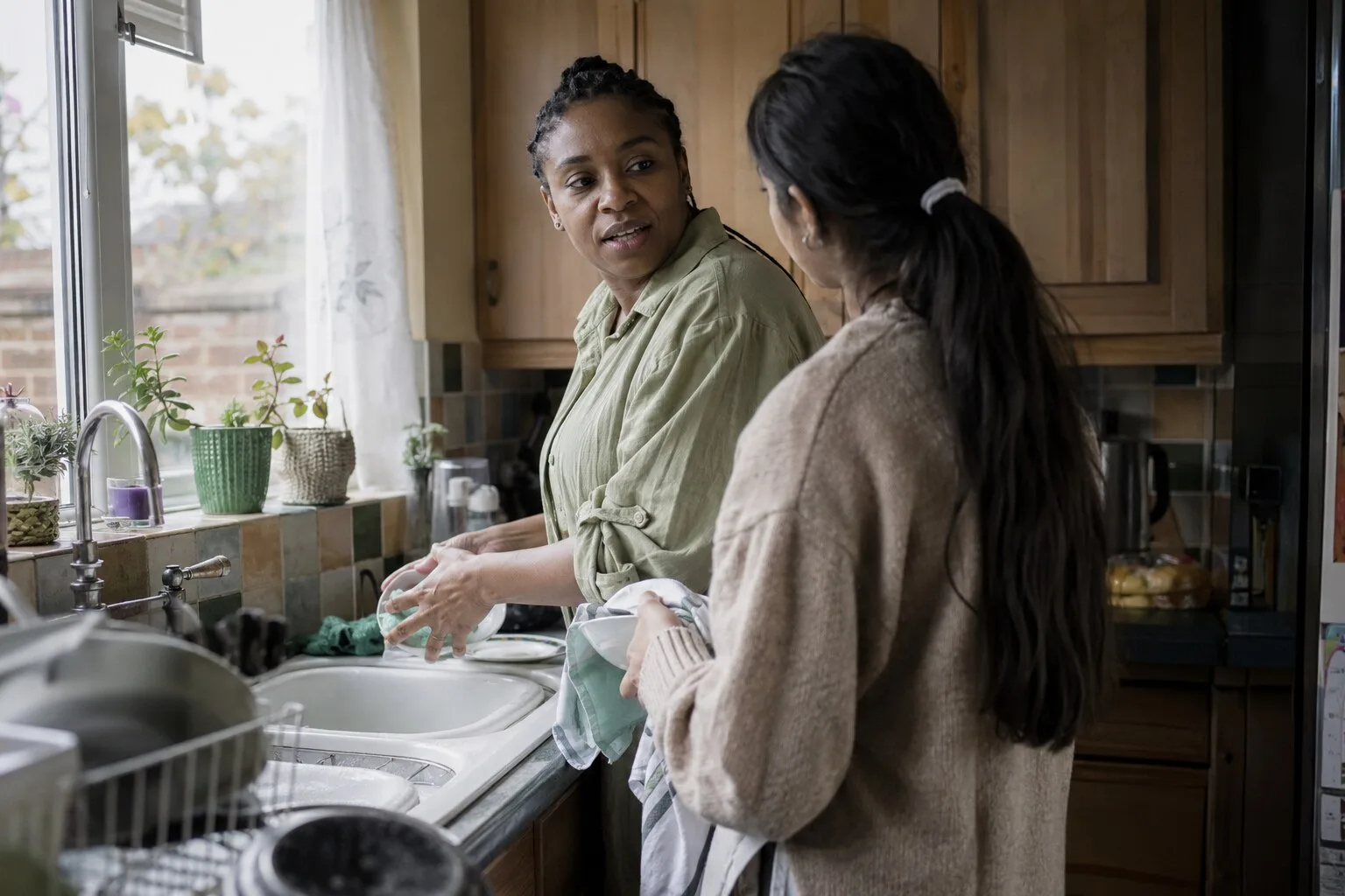 Two women talking together while washing up in a kitchen